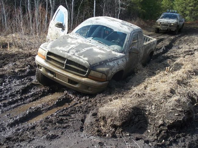 A truck is stuck in the mud on a muddy road.