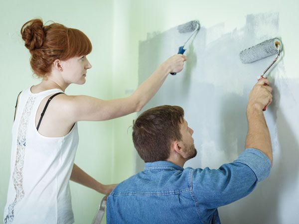 Woman and man rolling a green wall blue DIY painting.
