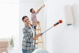 Man and a woman rolling walls painting white