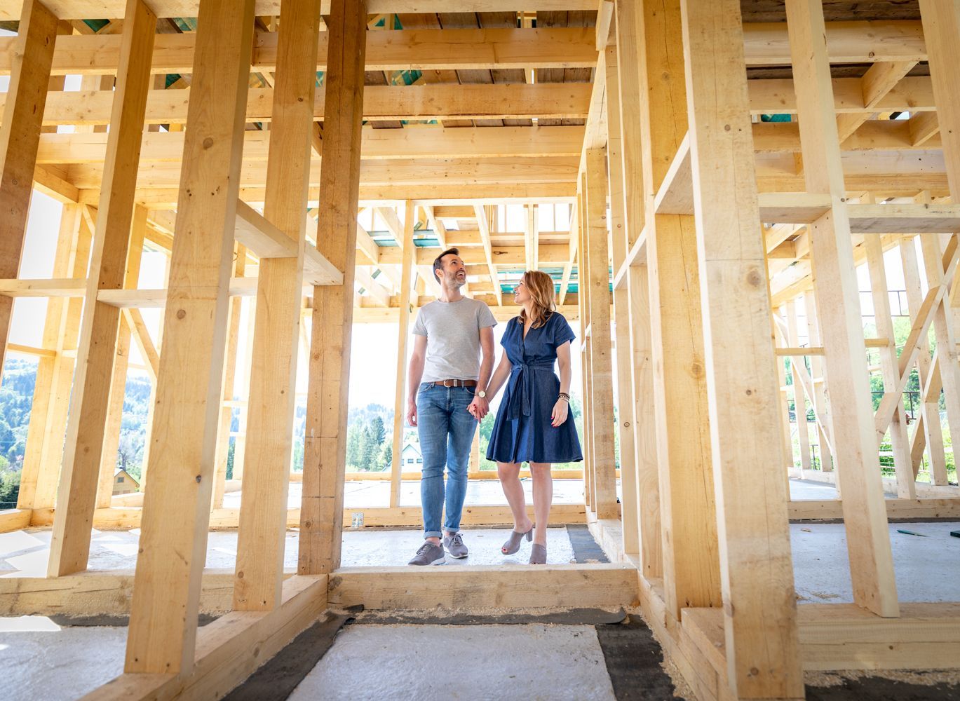 A man and a woman are holding hands in a wooden house under construction.