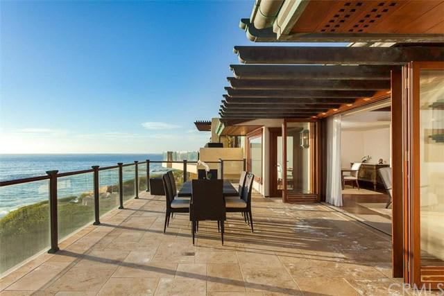 A balcony with a table and chairs overlooking the ocean.