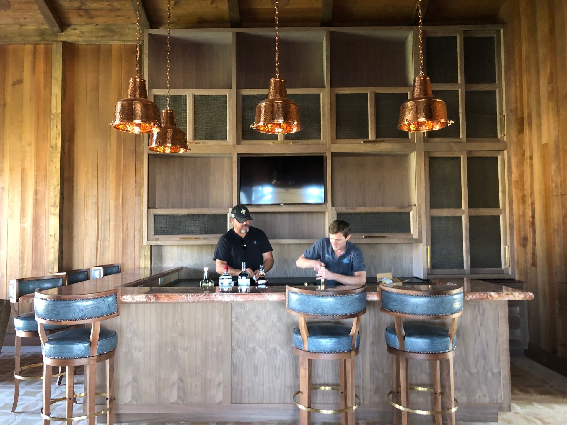 Two men are sitting at a bar in a wooden room.