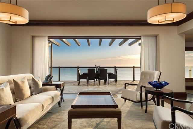 A living room with a couch, chairs, coffee table and a view of the ocean.