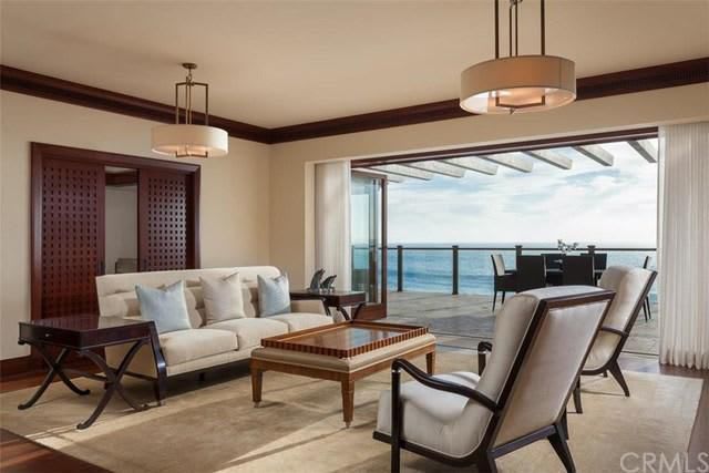 A living room with a couch and chairs and a view of the ocean.