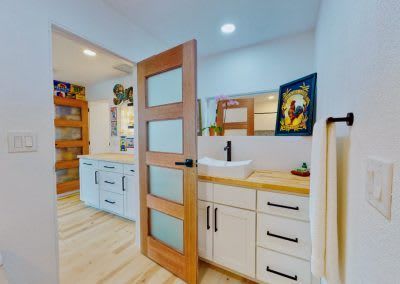 A bathroom with a sink, cabinets and a wooden door.