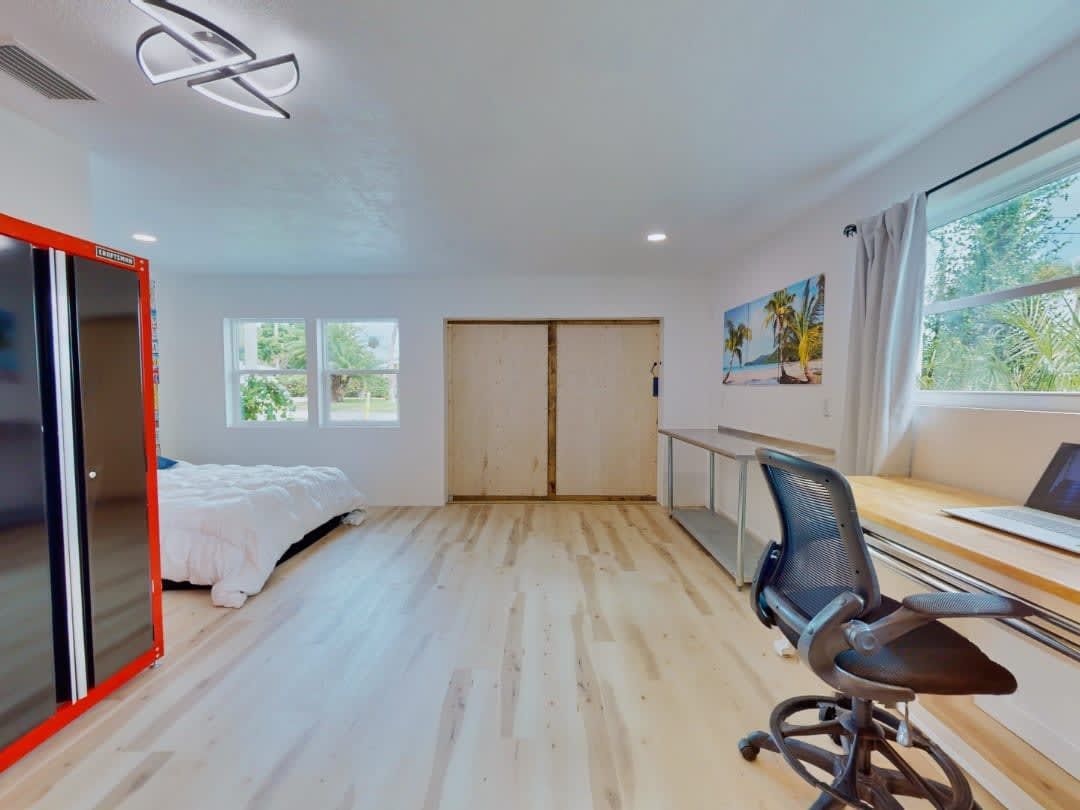 A bedroom with a desk and chair and a bed