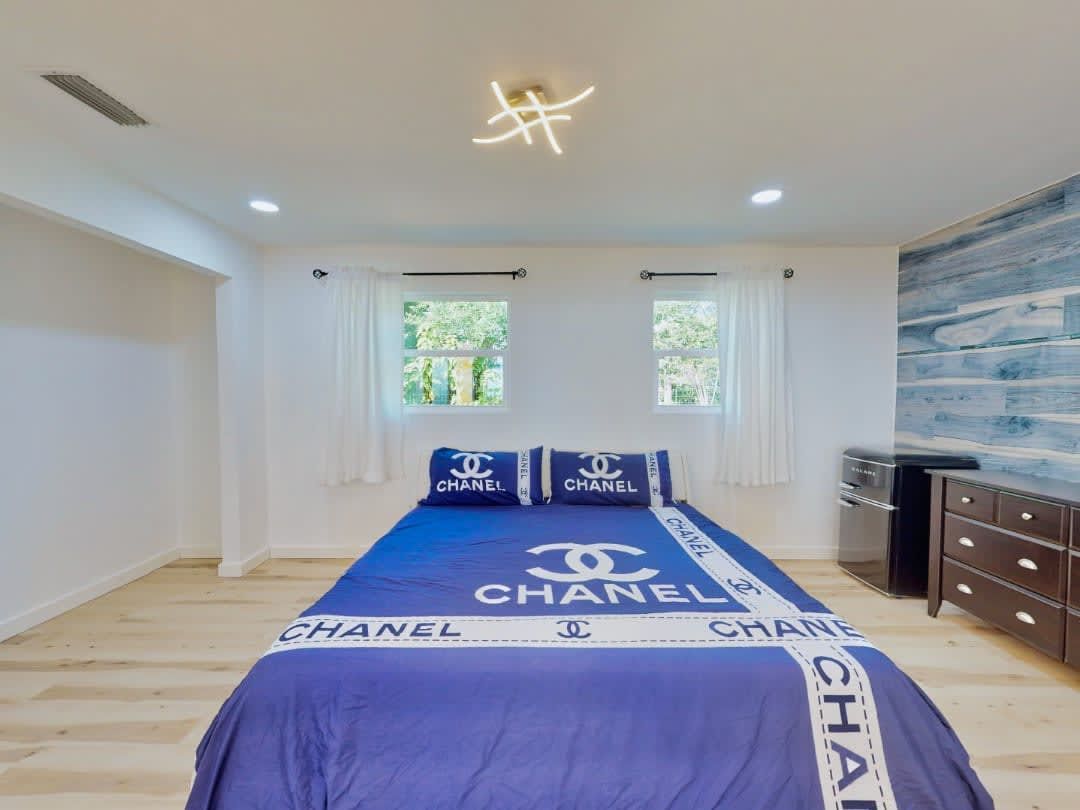 A bedroom with a chanel bedspread and pillows.