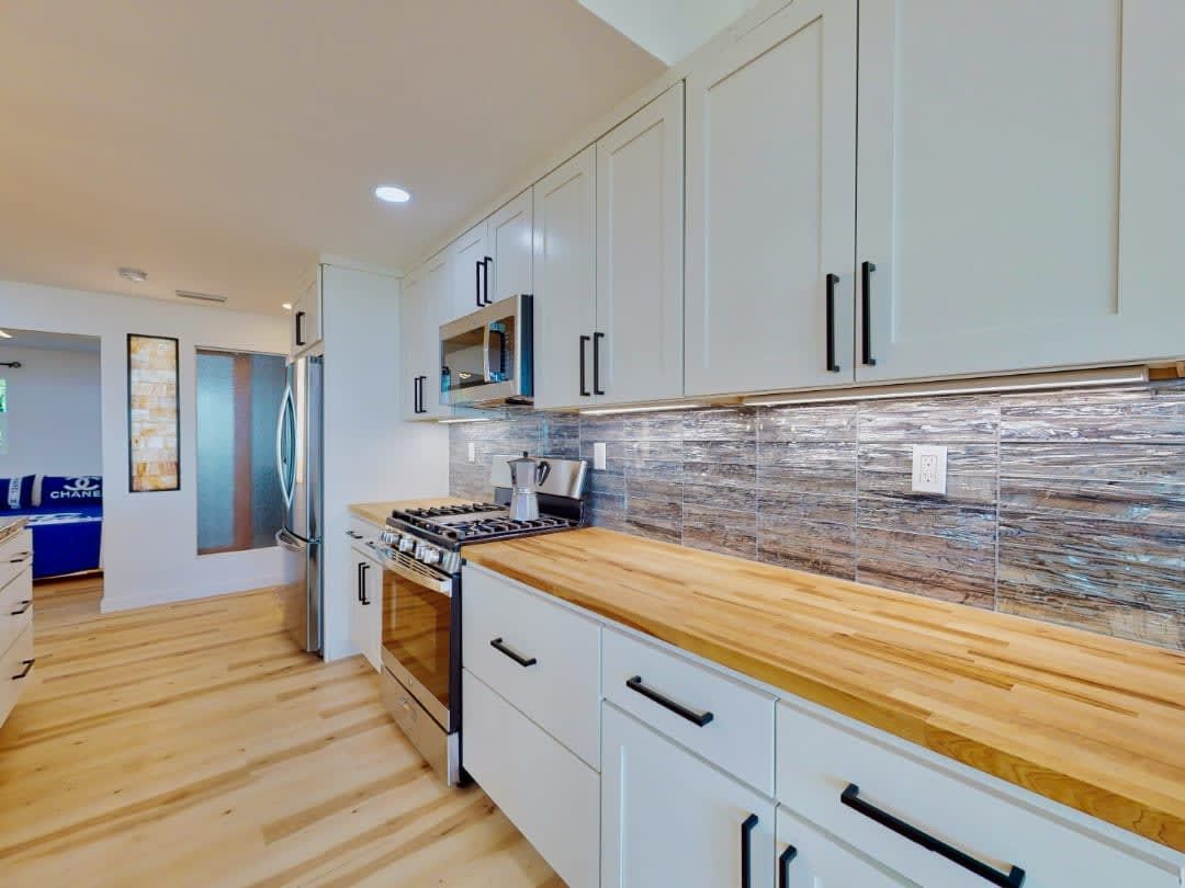 A kitchen with white cabinets and wooden counter tops.