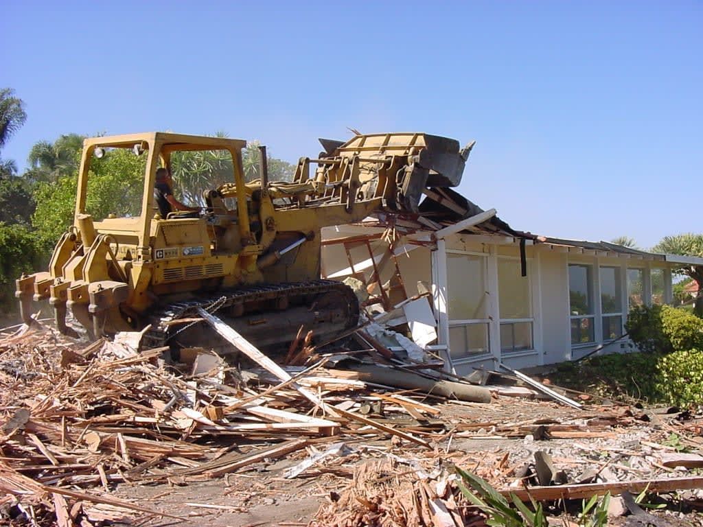 A house is being demolished by a bulldozer.