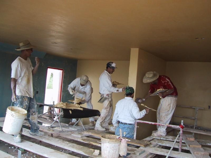 A group of men are painting a wall in a room.