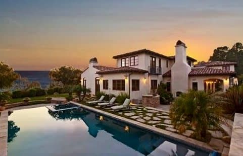 A large white house with a swimming pool in front of it.