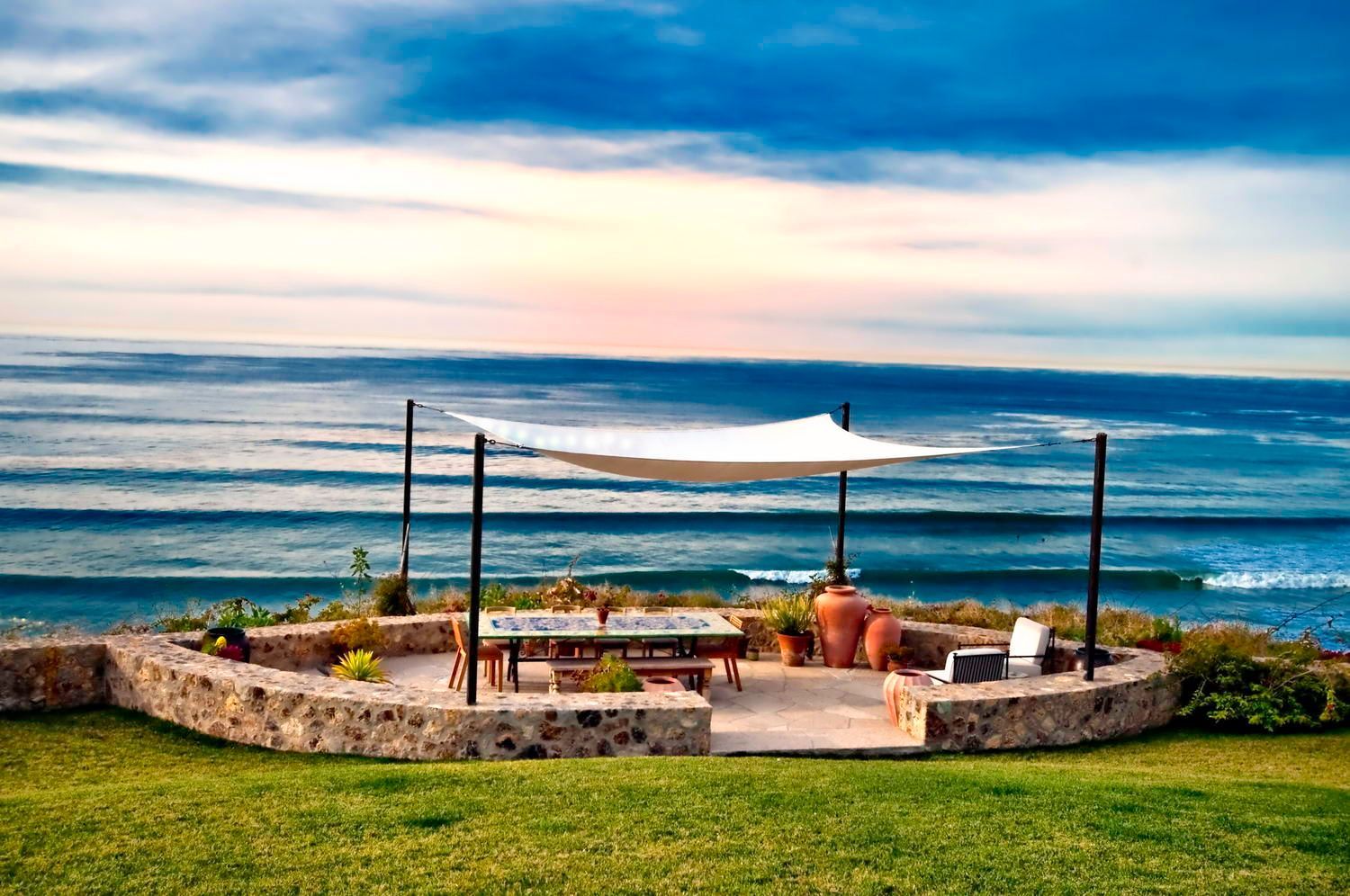 A patio with a canopy overlooking the ocean.