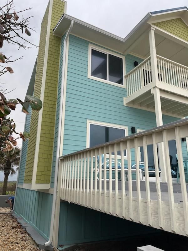 A blue and green house with a white deck.