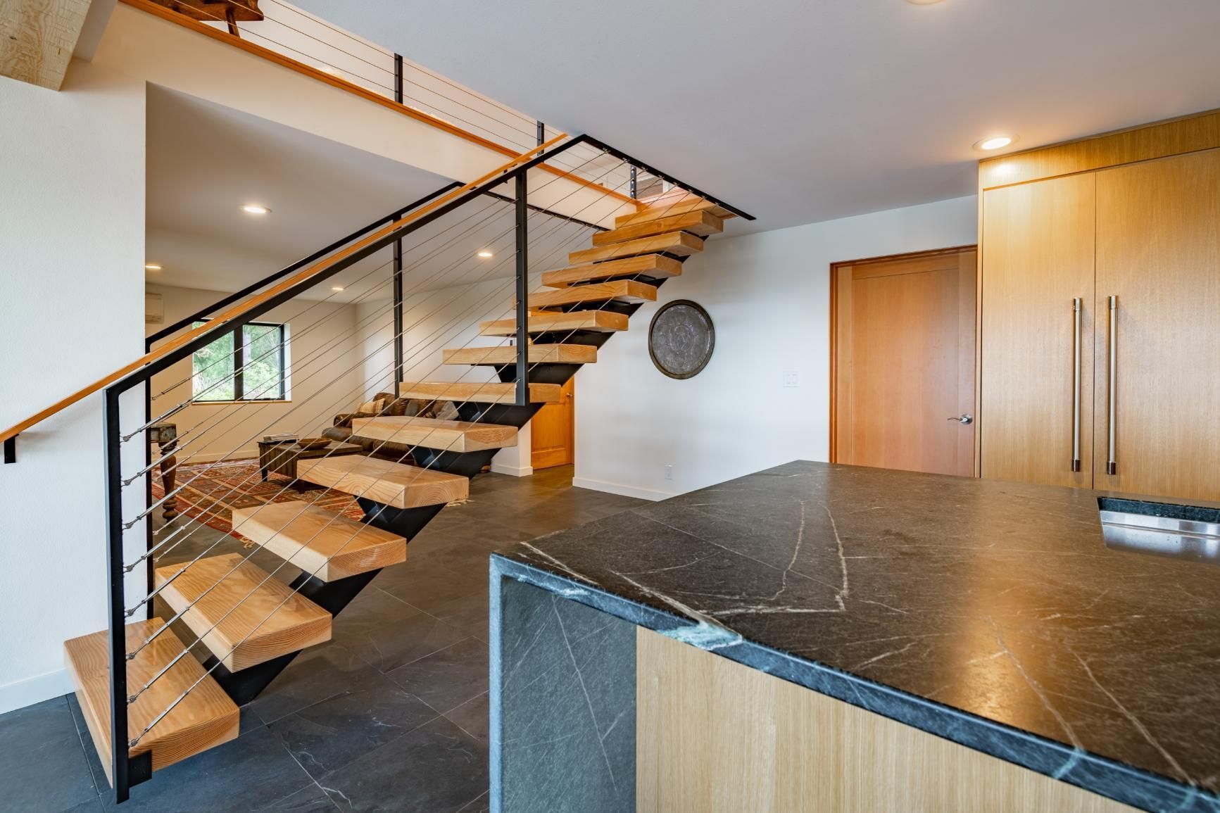 A kitchen with a wooden staircase leading up to the second floor.