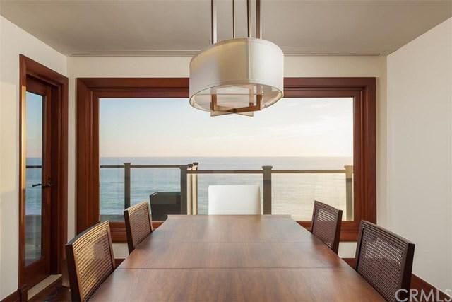 A dining room with a table and chairs and a view of the ocean.