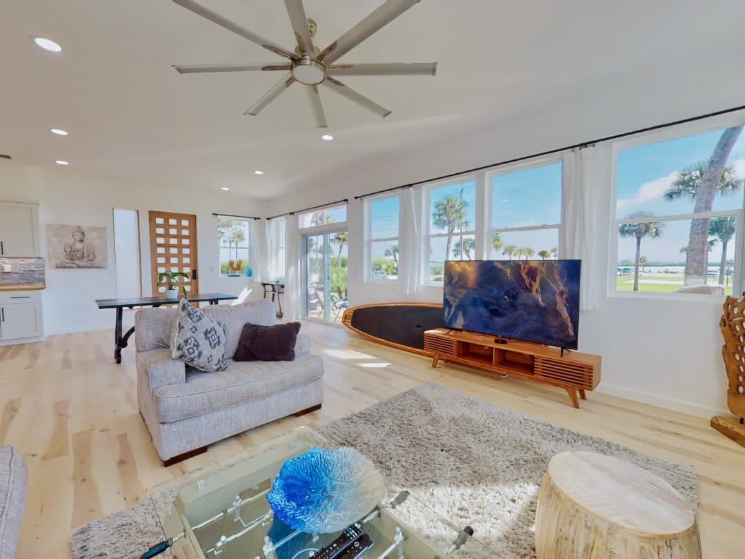 A living room with a couch, table, television and ceiling fan.