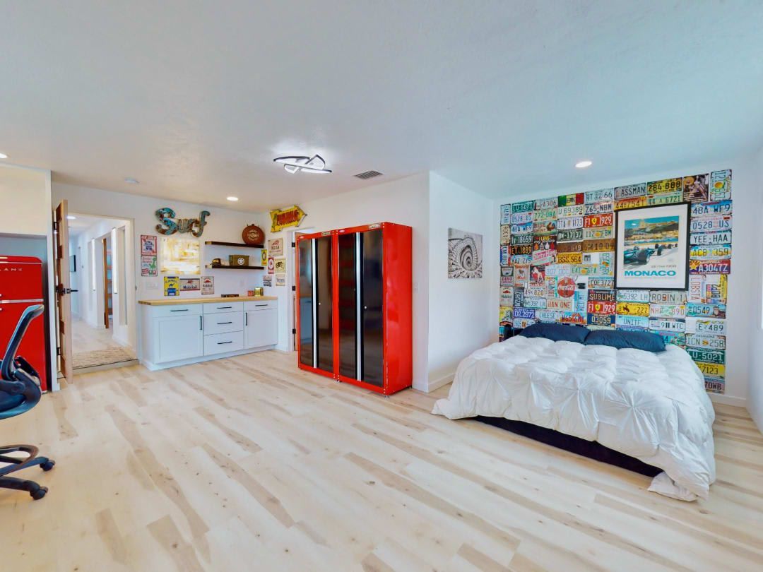 A bedroom with a bed, desk, chair and a red wardrobe.