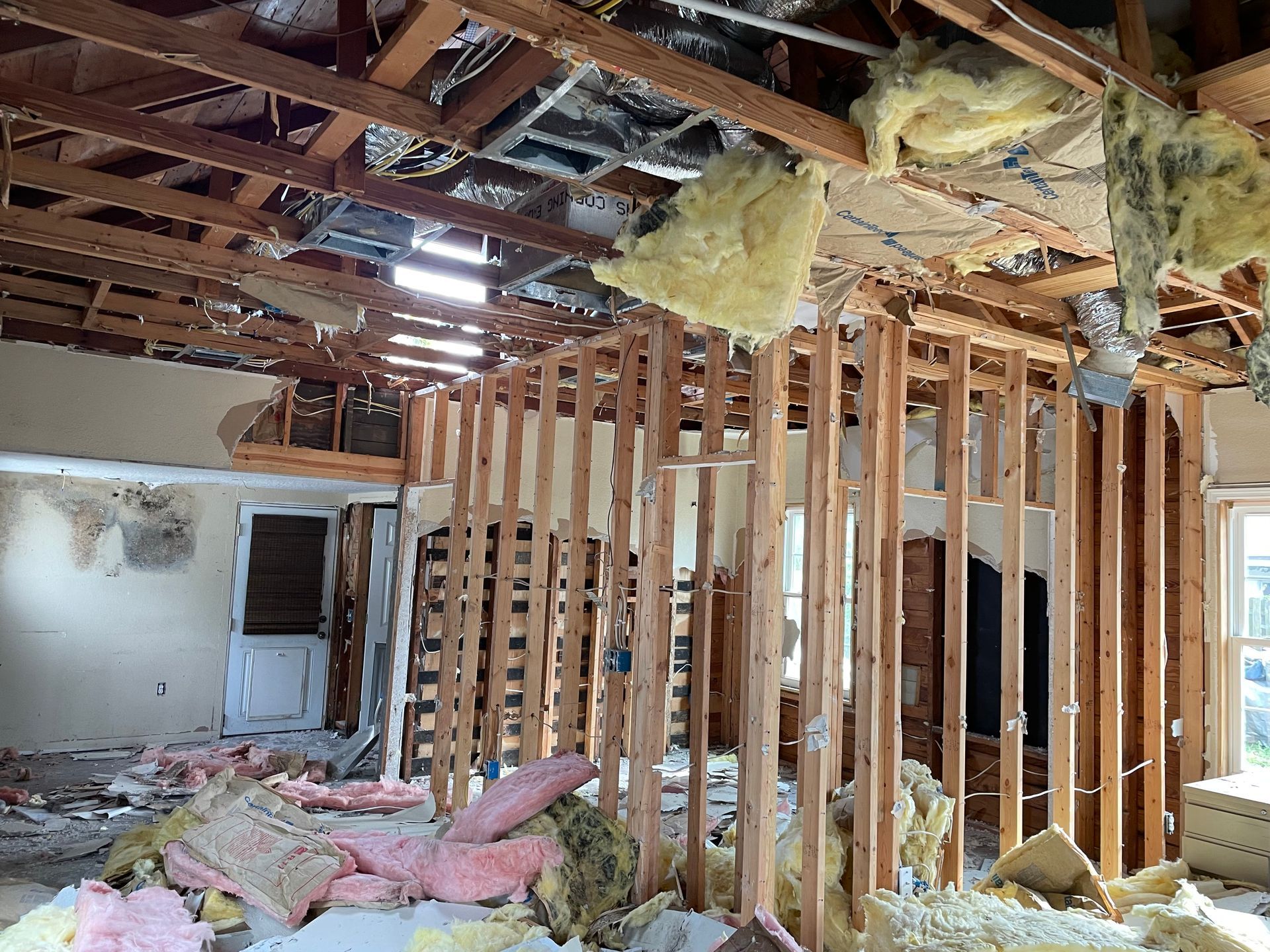 A room with a lot of wooden beams and insulation hanging from the ceiling.