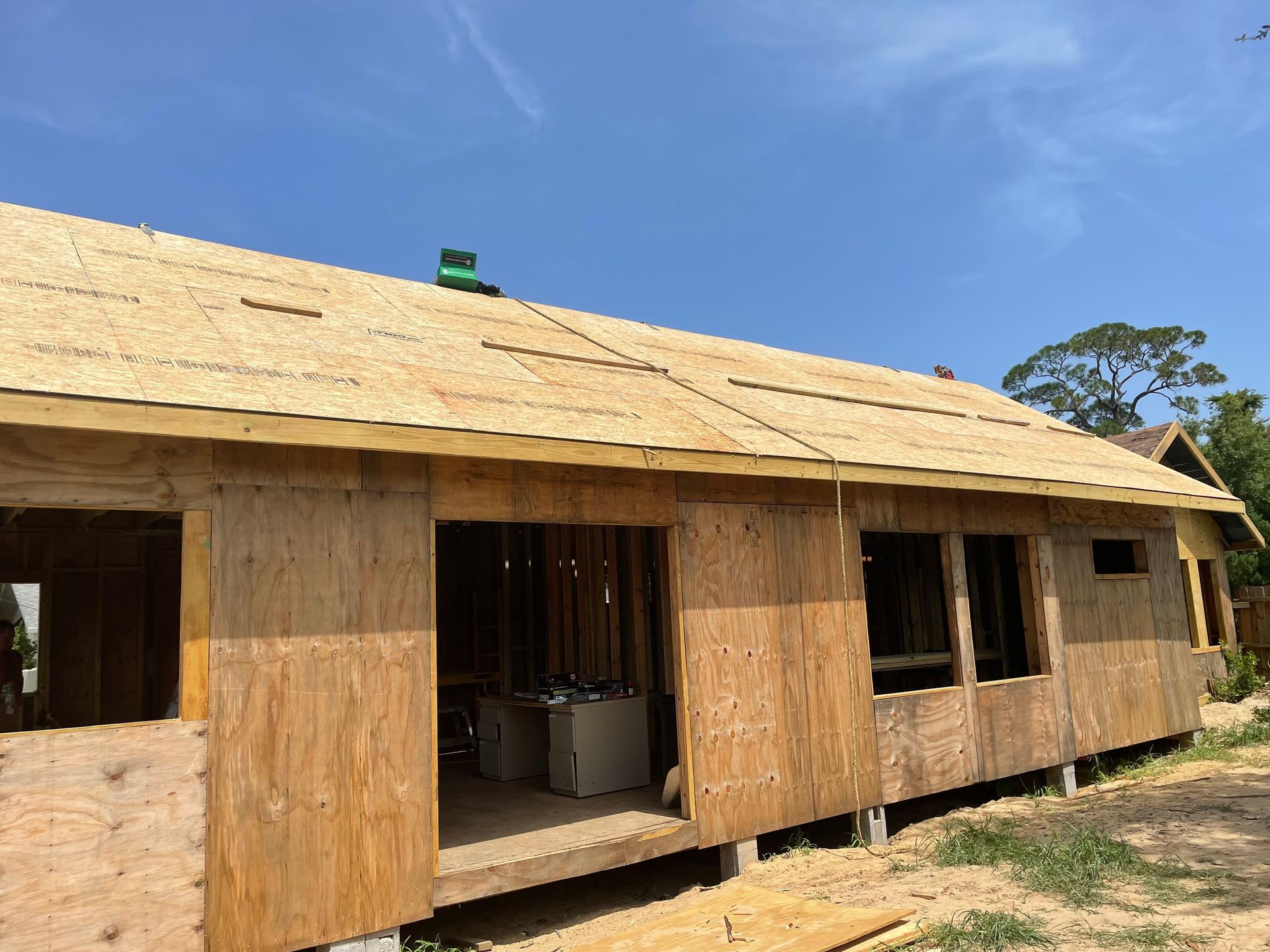 A wooden house is being built with a blue sky in the background.
