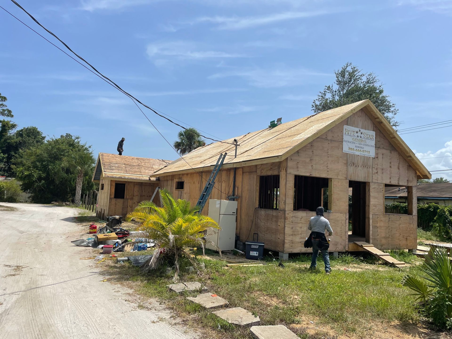 A man is standing in front of a house that is being built.