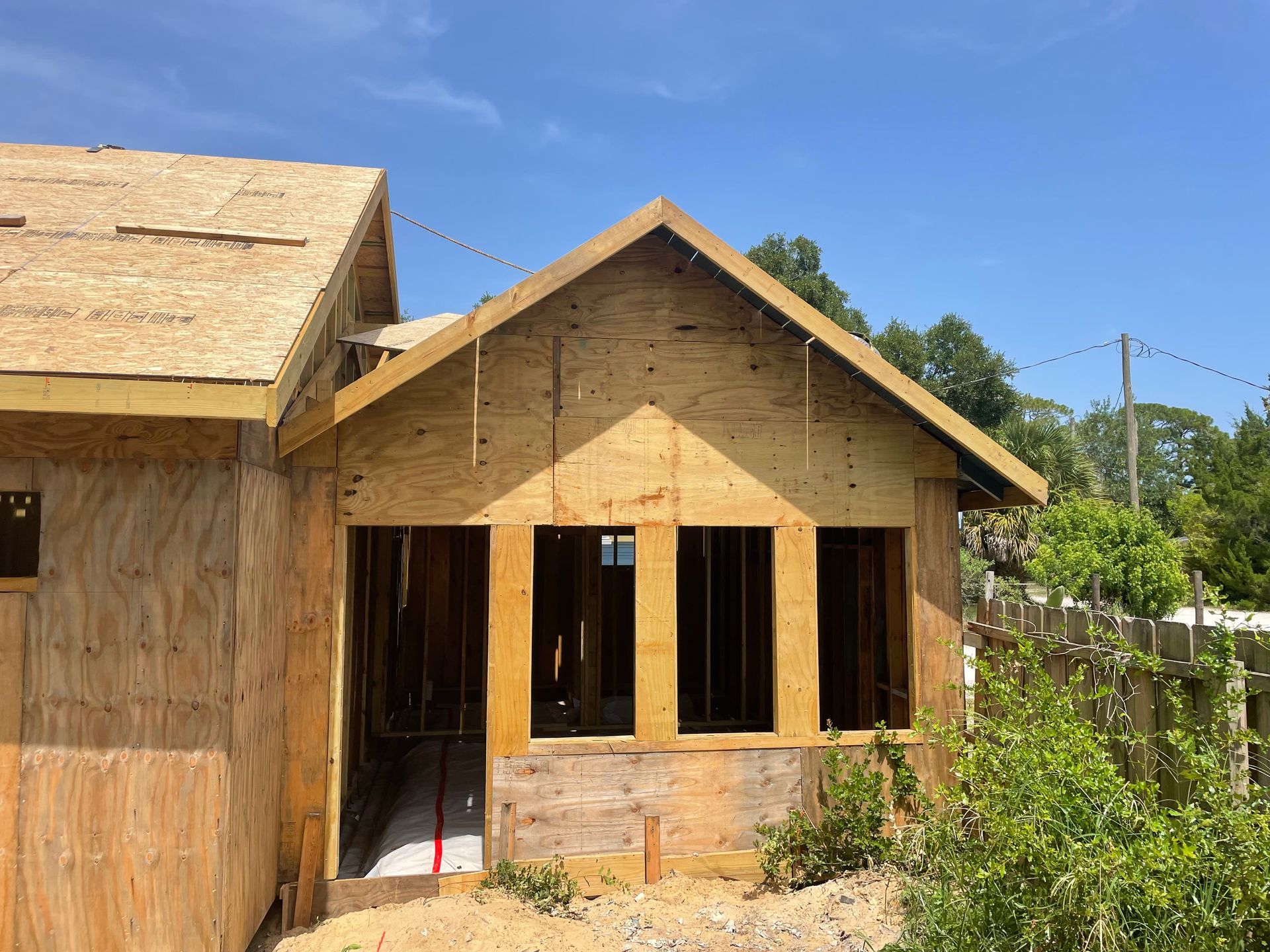 A wooden house is being built with a blue sky in the background.