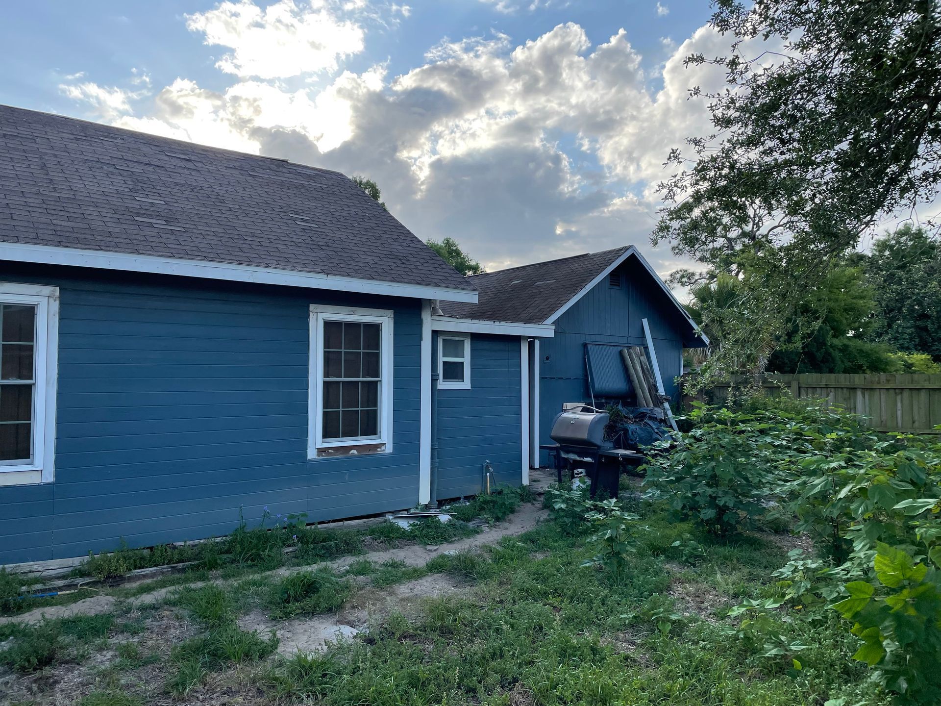 A narrow hallway between two blue houses with a wooden floor.