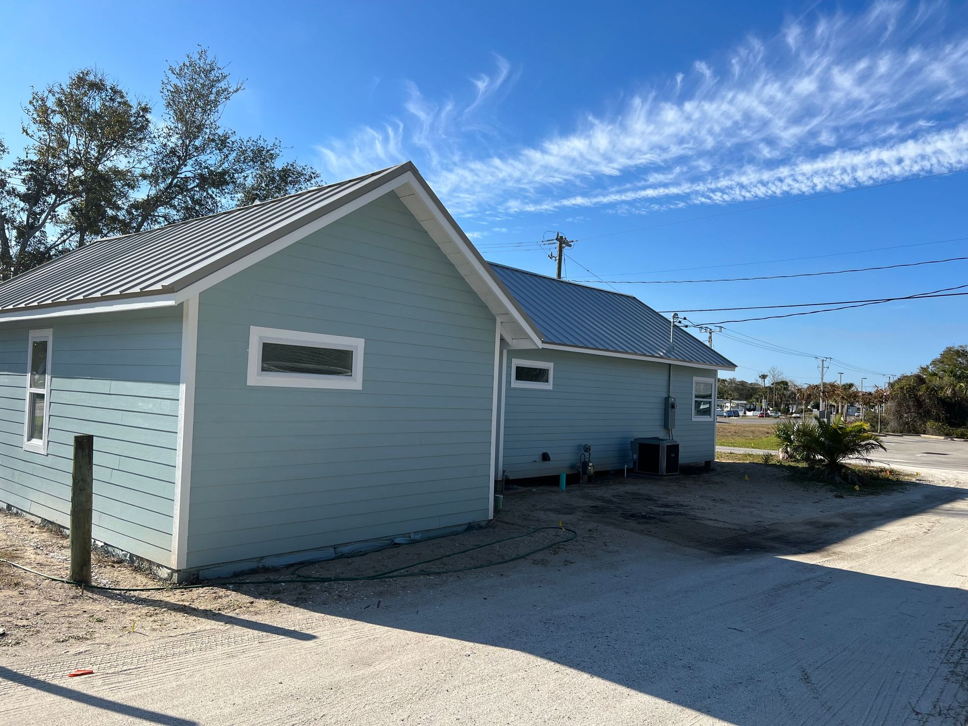 A blue house with a white trim and a metal roof.