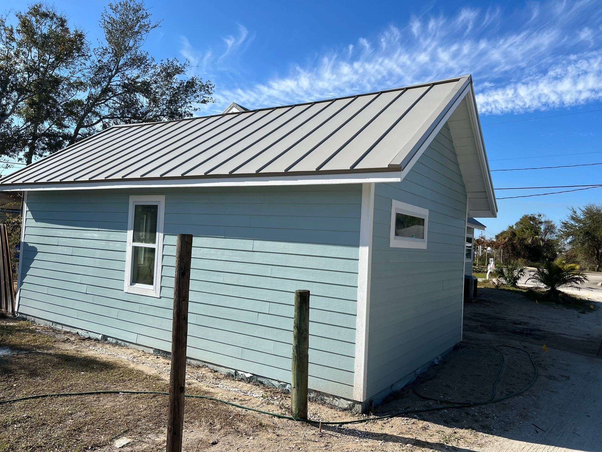 A small house with a metal roof and blue siding.