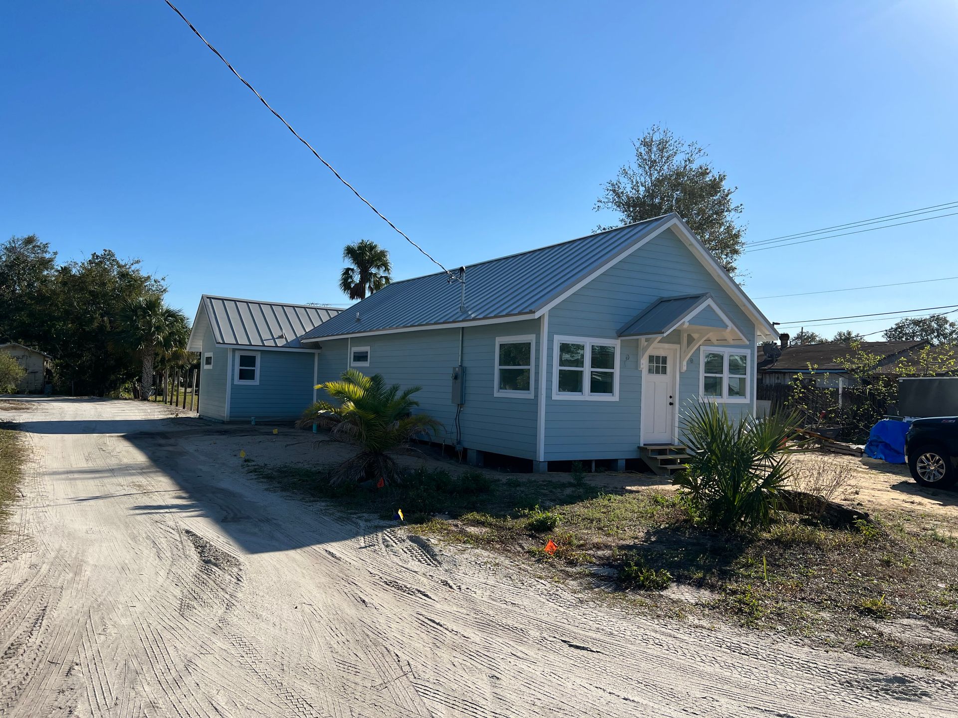 A small house is sitting on the side of a dirt road.