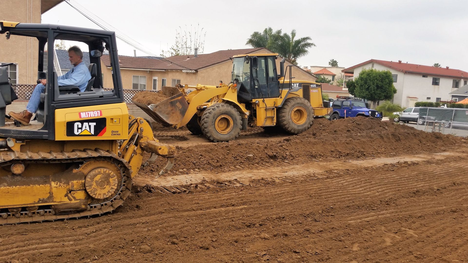 A man is driving a cat bulldozer on a dirt road.