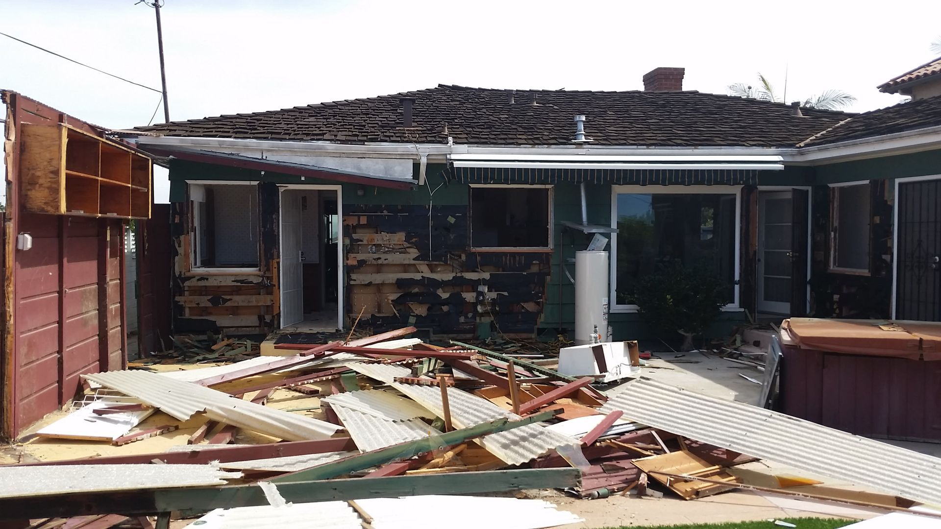 A house is being demolished and there is a pile of wood in front of it.