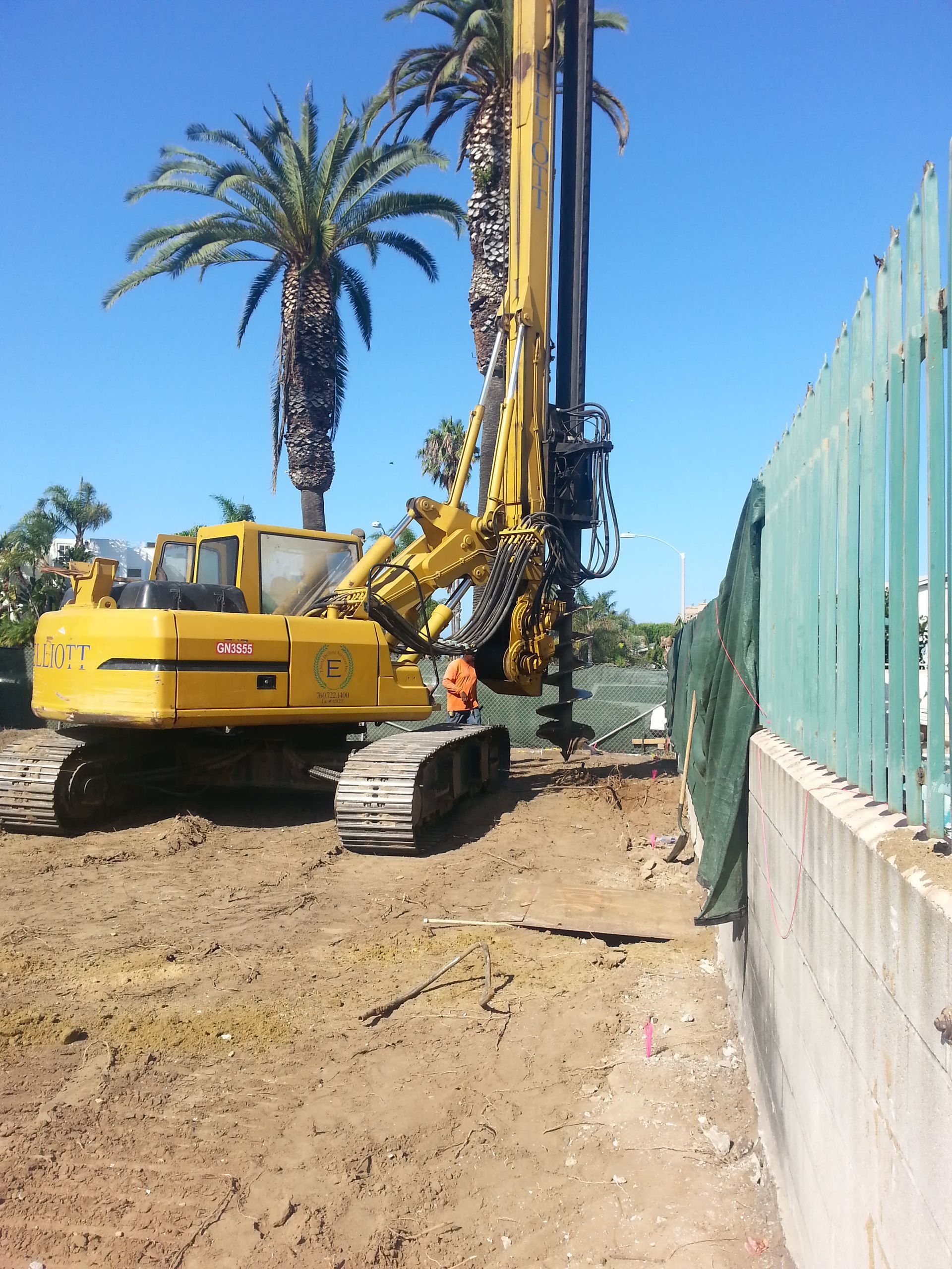 A yellow excavator with a drill attached to it.