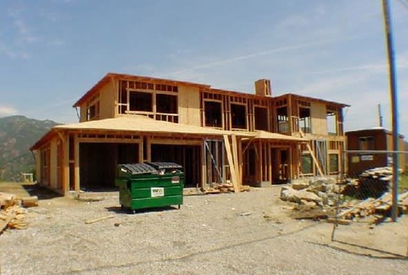 A green dumpster sits in front of a house under construction.