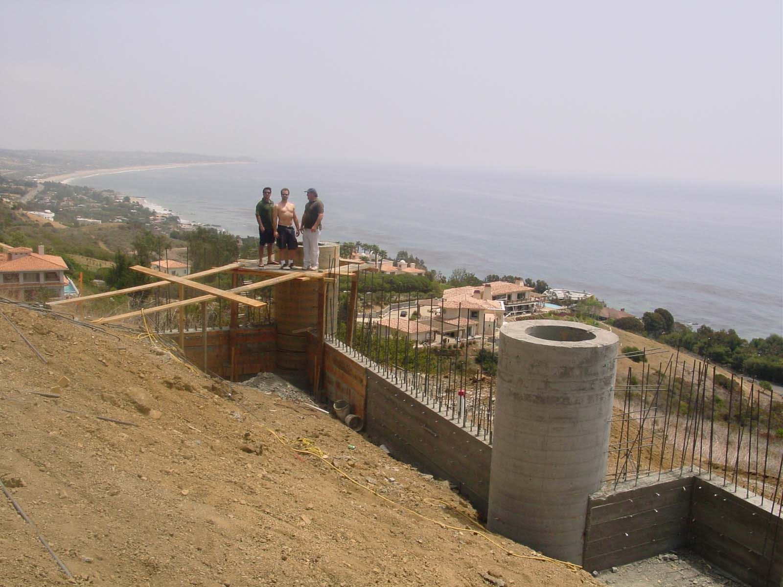A group of people standing on top of a hill overlooking the ocean.