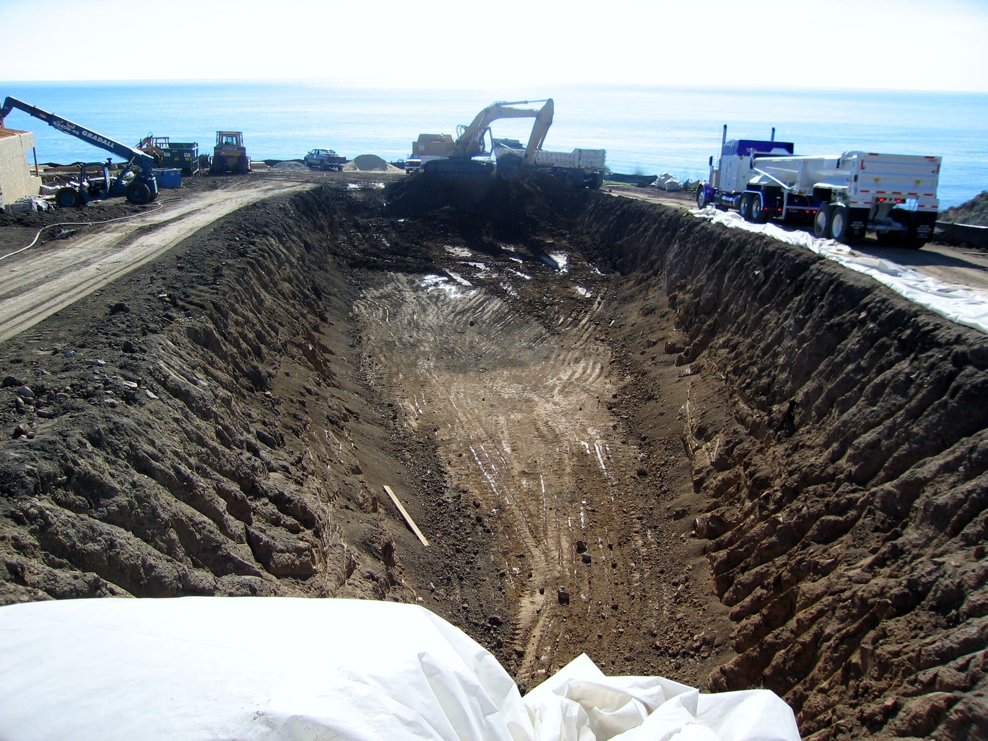A large hole in the ground with a truck in the background.