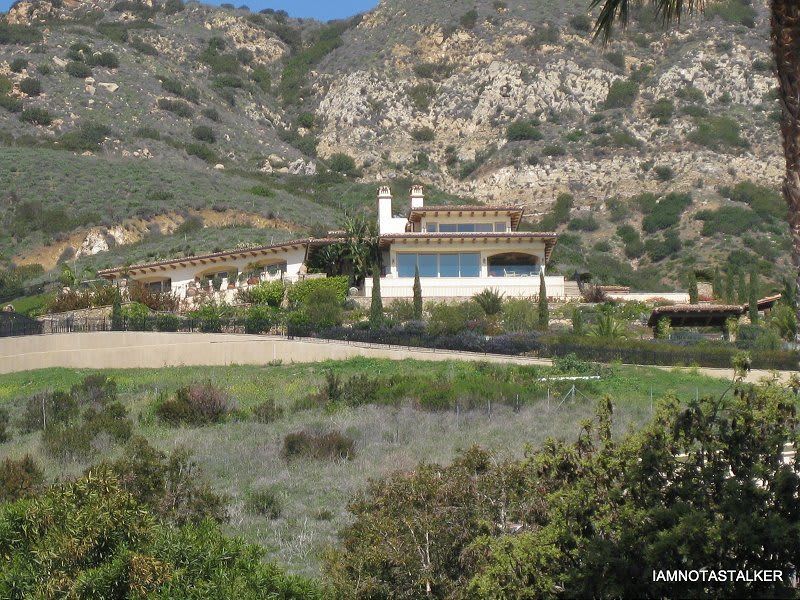 A large house sits in the middle of a lush green field.