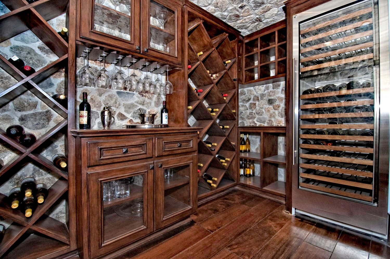 A wine cellar with lots of wine bottles and glasses on shelves.