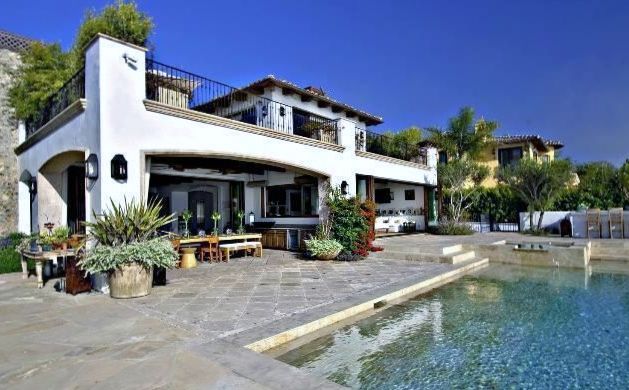 A large white house with a swimming pool in front of it.