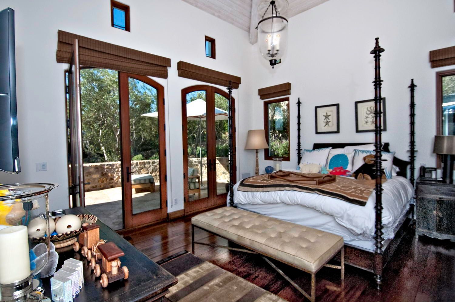 A bedroom with a four poster bed and sliding glass doors.