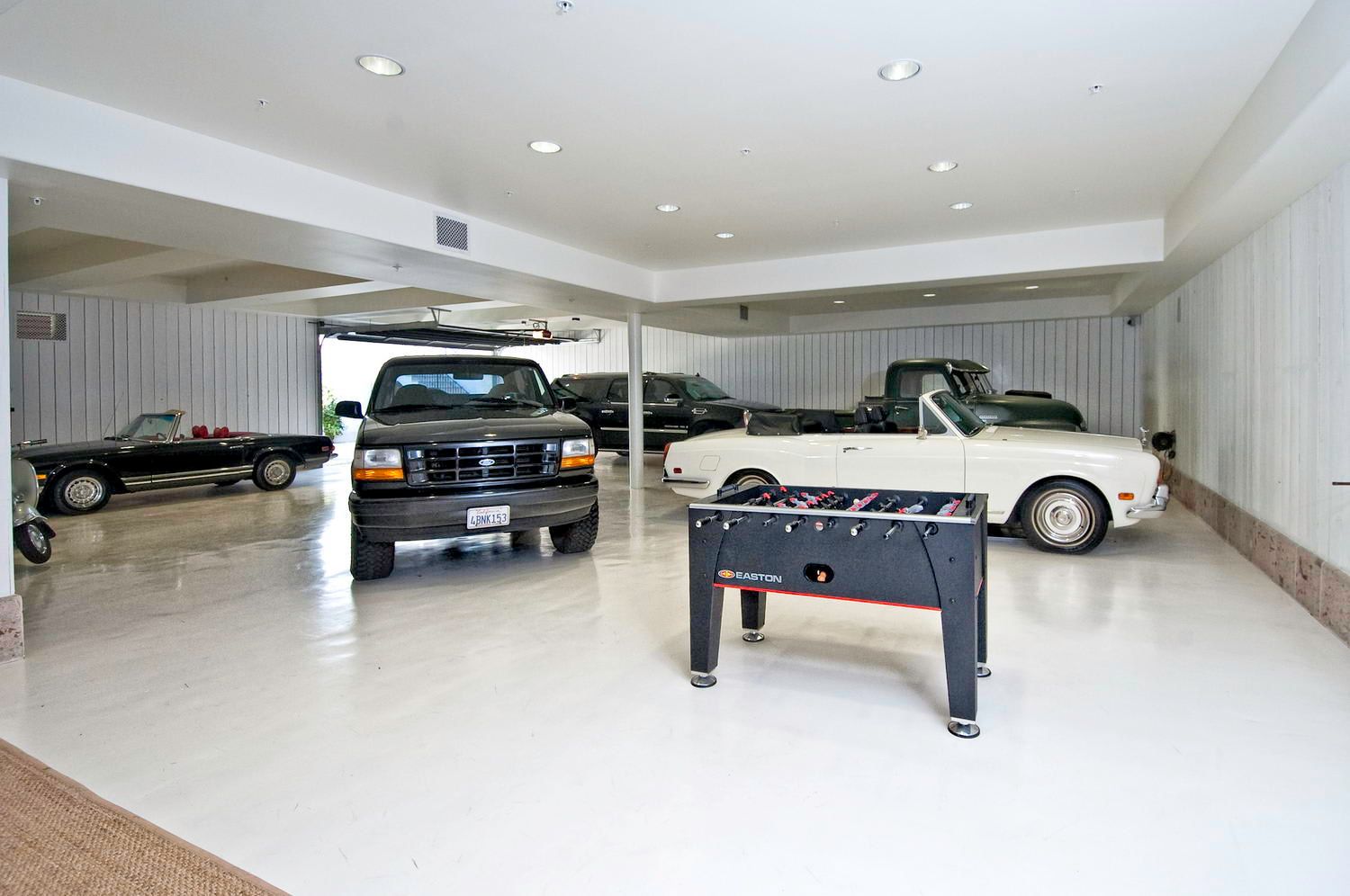 A garage filled with cars and a foosball table.