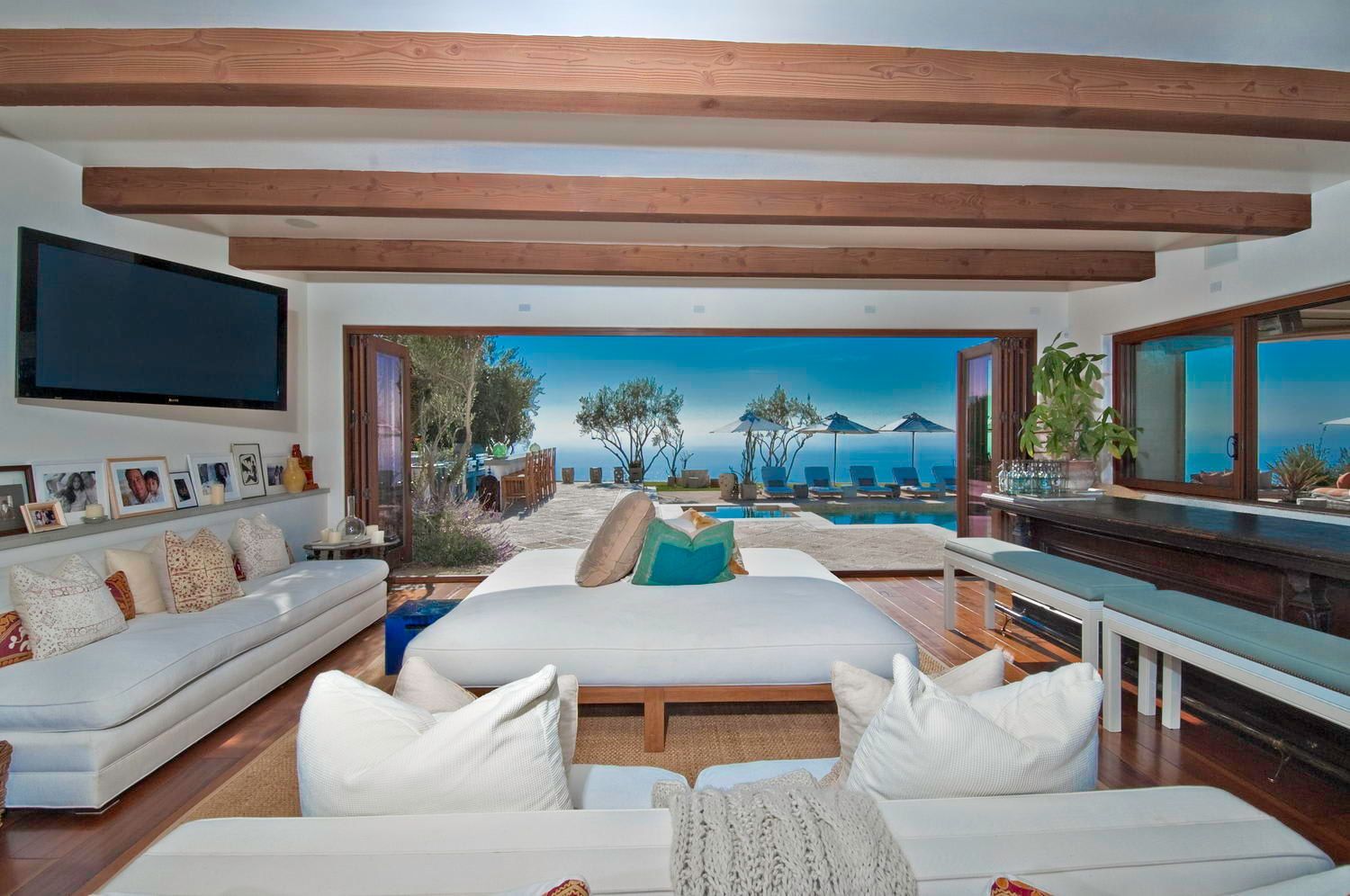 A living room filled with furniture and a television with a view of the ocean.