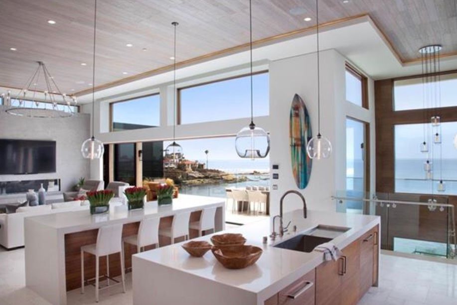 A kitchen with a large island and a surfboard on the wall.