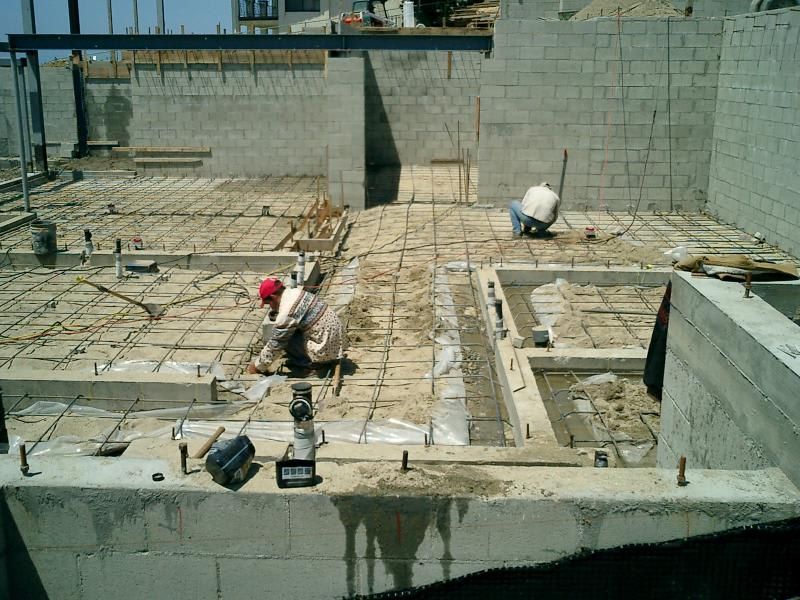 A group of construction workers are working on a concrete floor.