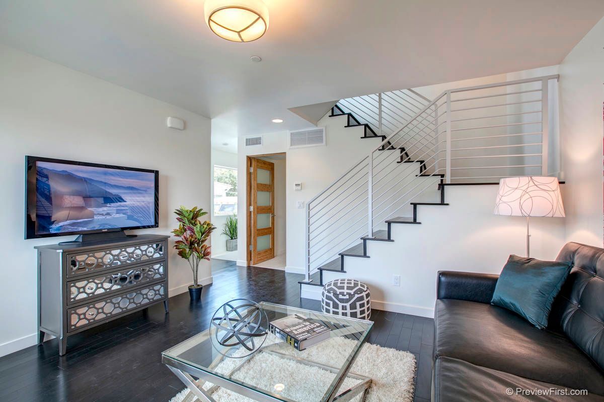 A living room with a couch , table , television and stairs.