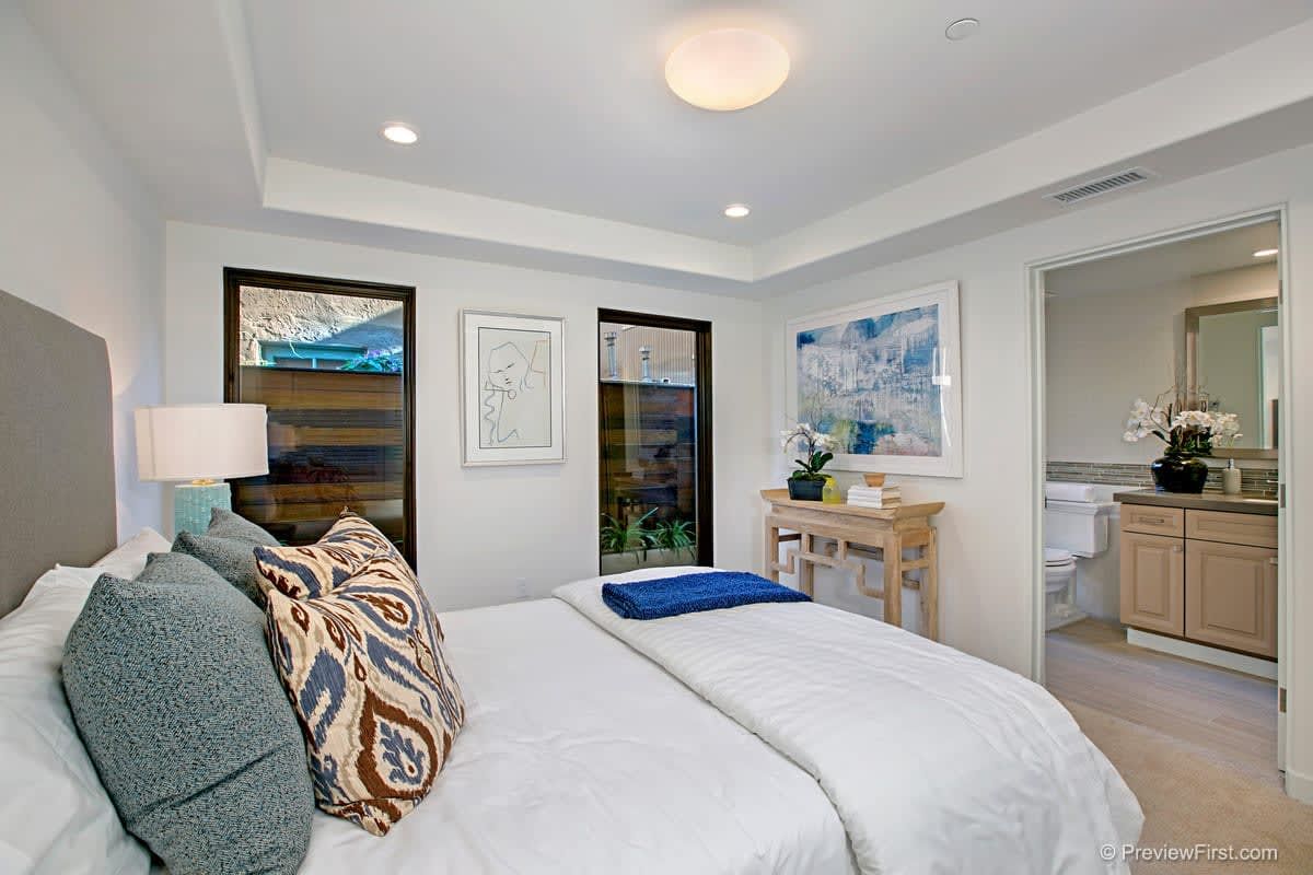 A bedroom with a large bed and a bathroom in the background.