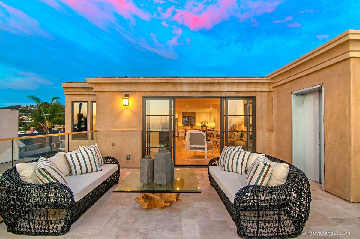 A patio with a couch and chairs and a glass table.