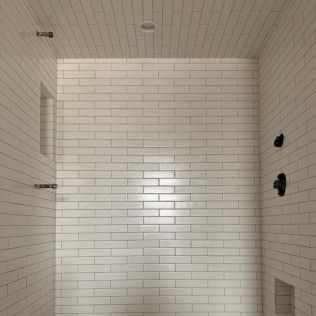 White tiled shower with a recessed shelf and fixtures.