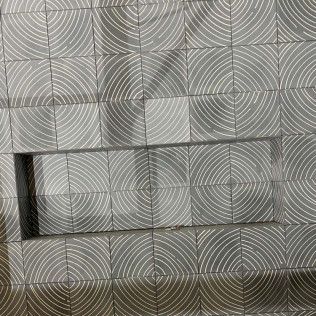 Gray and white tiled wall with a rectangular opening. Curved lines decorate the tiles.