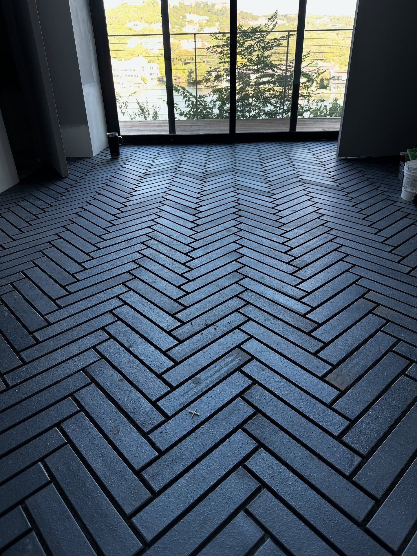 Blue herringbone tile floor in front of a window overlooking an outdoor view.