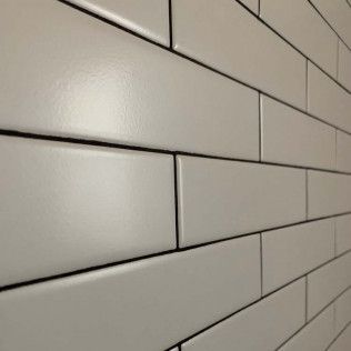 White rectangular tiles on a wall, with black grout lines, creating a geometric pattern.